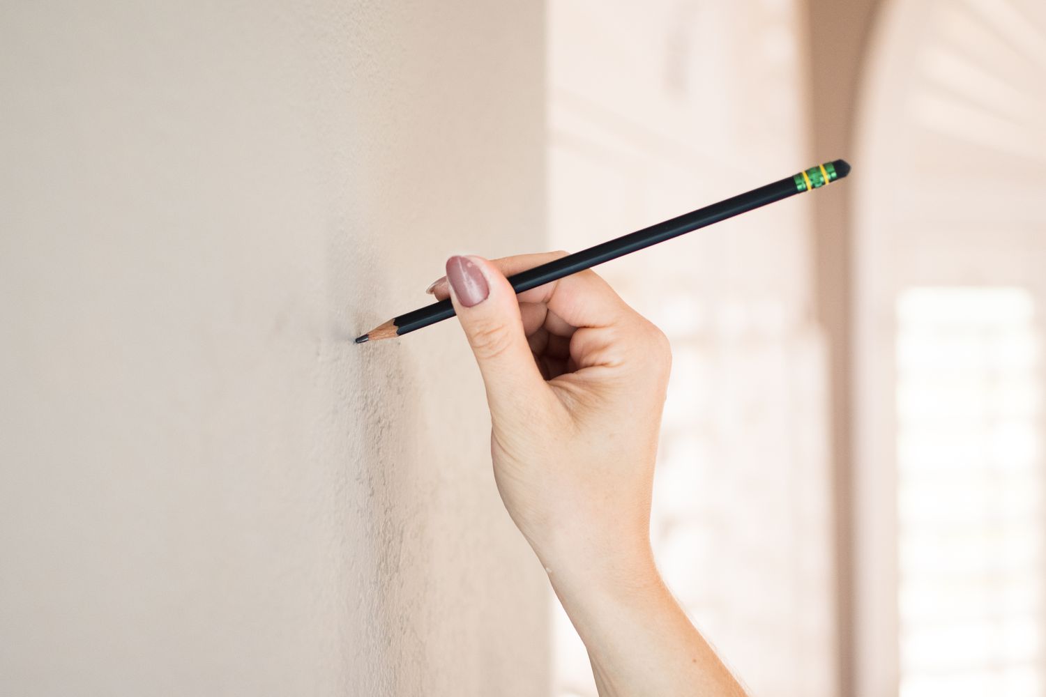 Pencil marking placement on wall for picture hanging