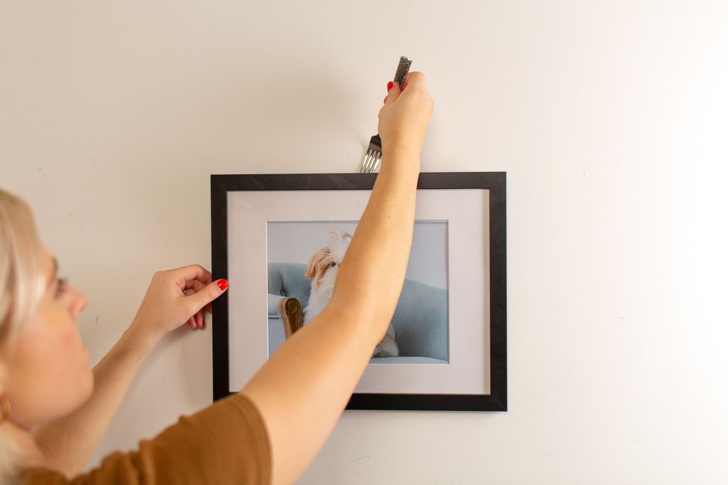 Woman hanging picture frame with fork