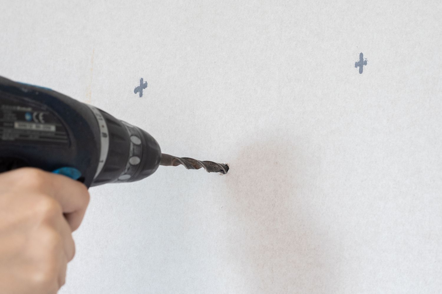 Electric drill making holes in walls on x markings 