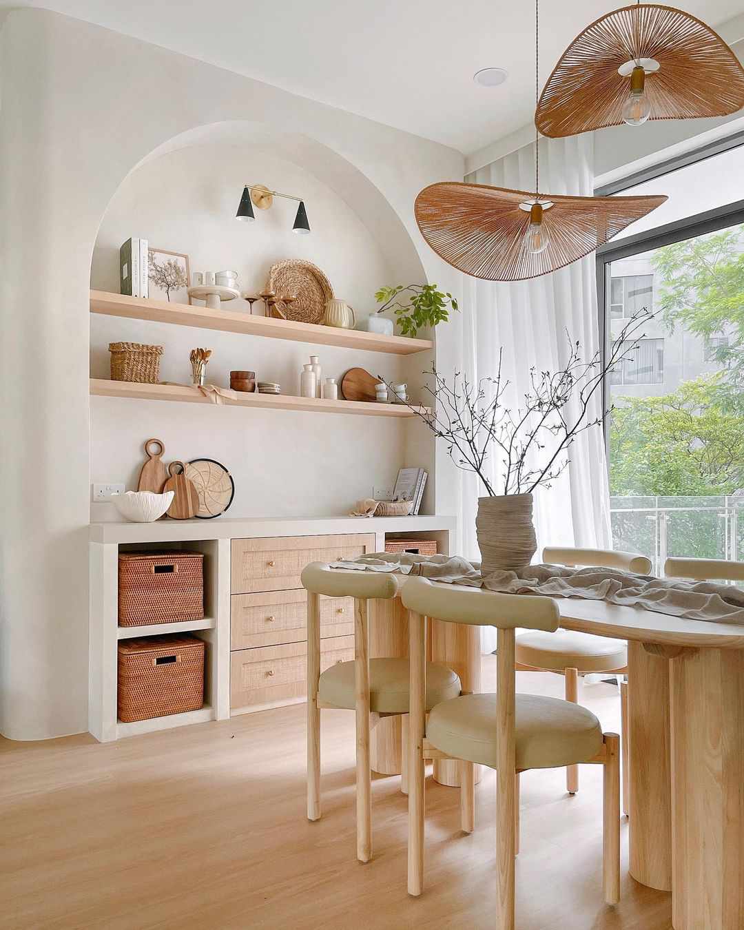 A modern organic dining room with an arched built-in shelf and abstract rattan pendant lights
