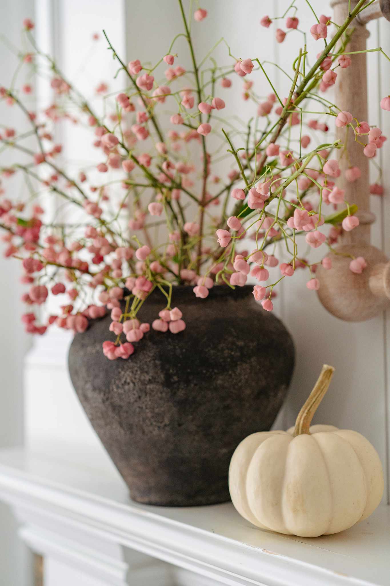 Vase with branches and a white pumpkin next to it
