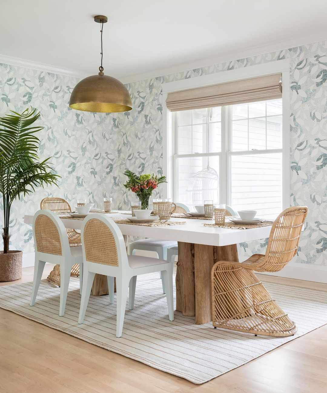 Whimsical dining room with blue wallpaper, cane backed dining chairs, and wicker S chairs