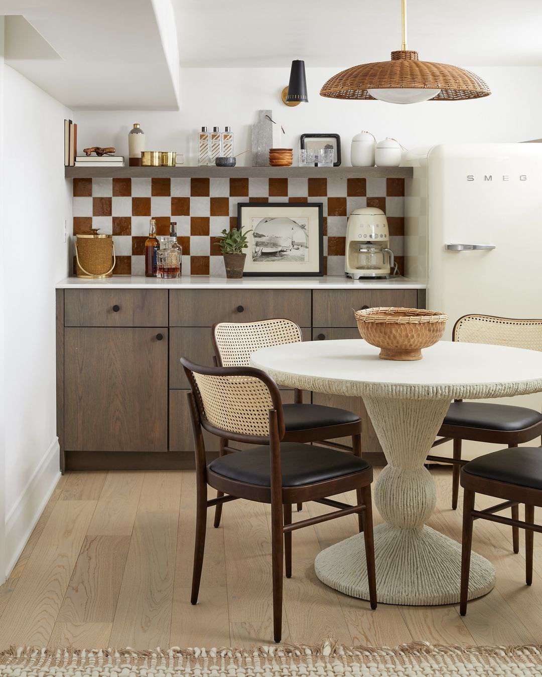 Postmodern eclectic dining room in a kitchen nook with plaster pedestal table, cane Bauhaus chairs, and wicker pendant