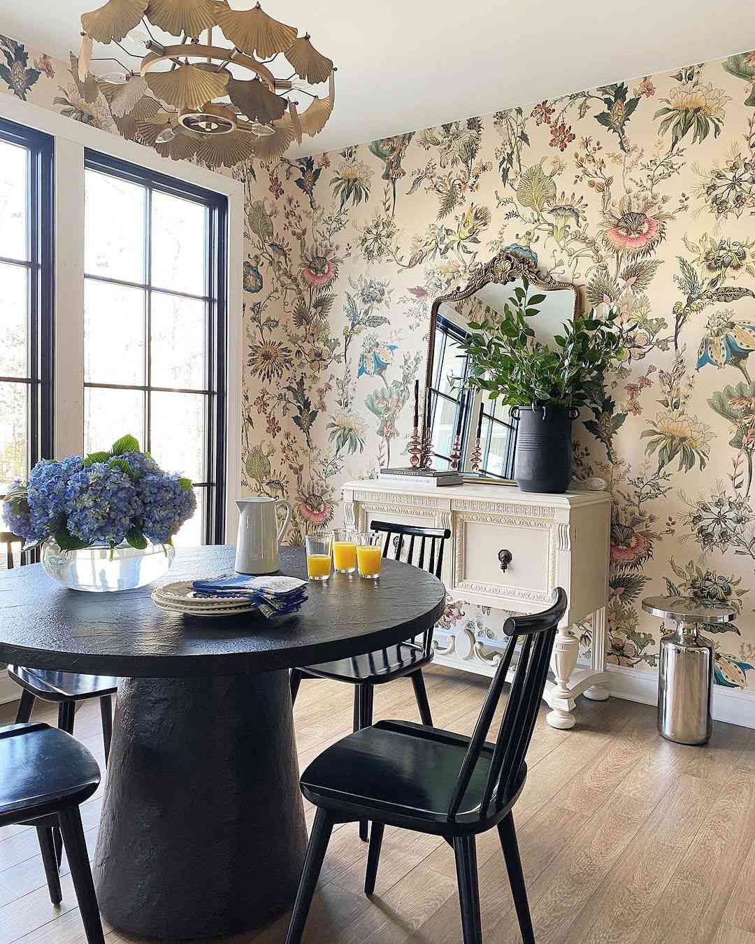 Small dining room with floral wallpaper, brass gingko chandelier, and black pedestal dining set