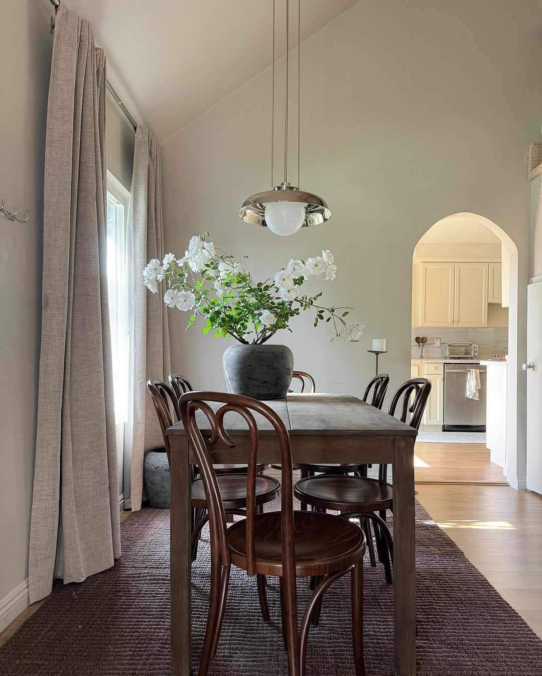 Dining room with rust farm table, industrial chrome pendant, and thonet style bentwood back cafe chairs