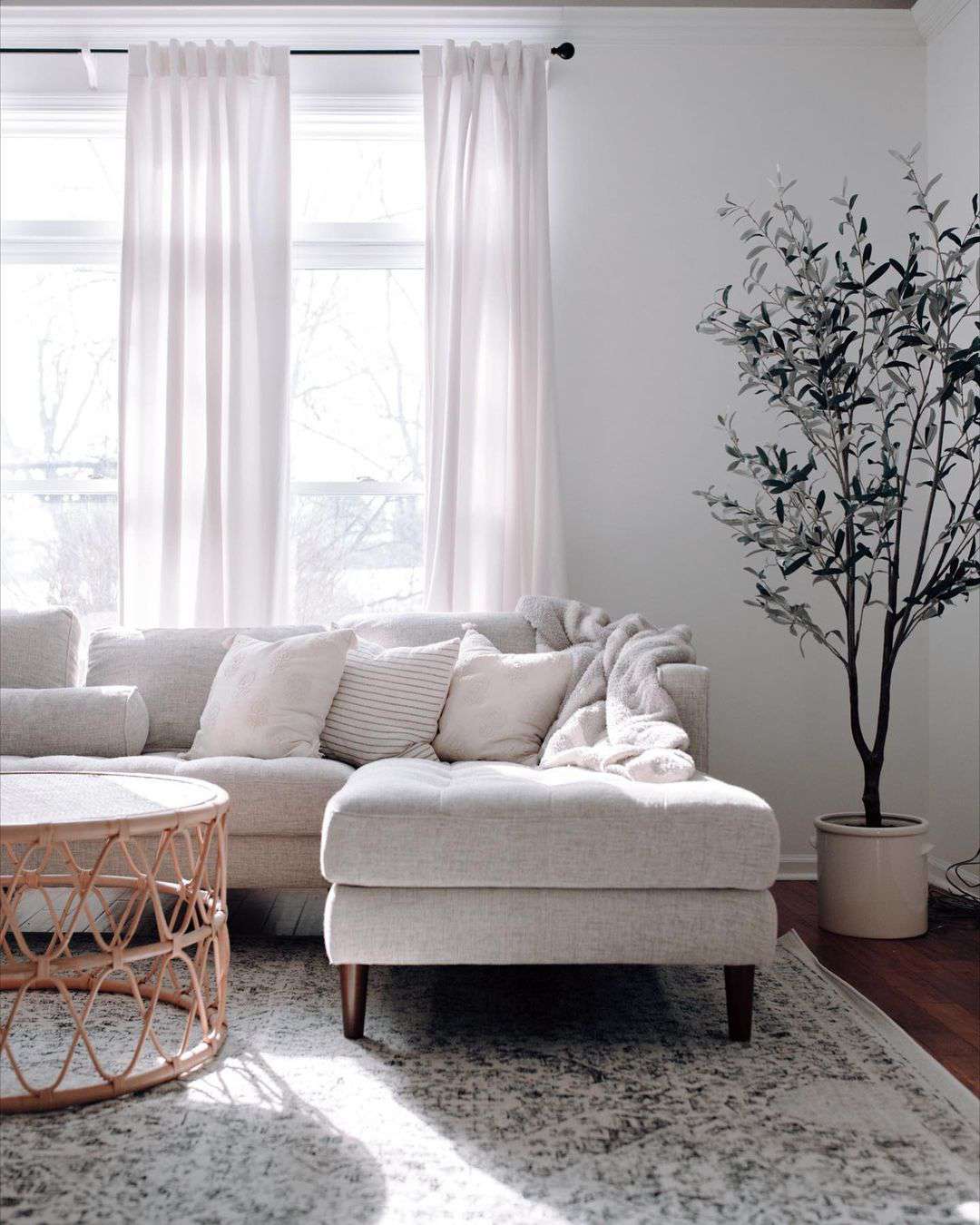 A light and airy neutral living room with long floor-to-ceiling white curtains