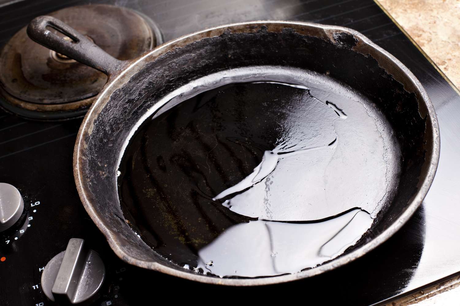 Old cast iron skillet being cleaned with a layer of oil